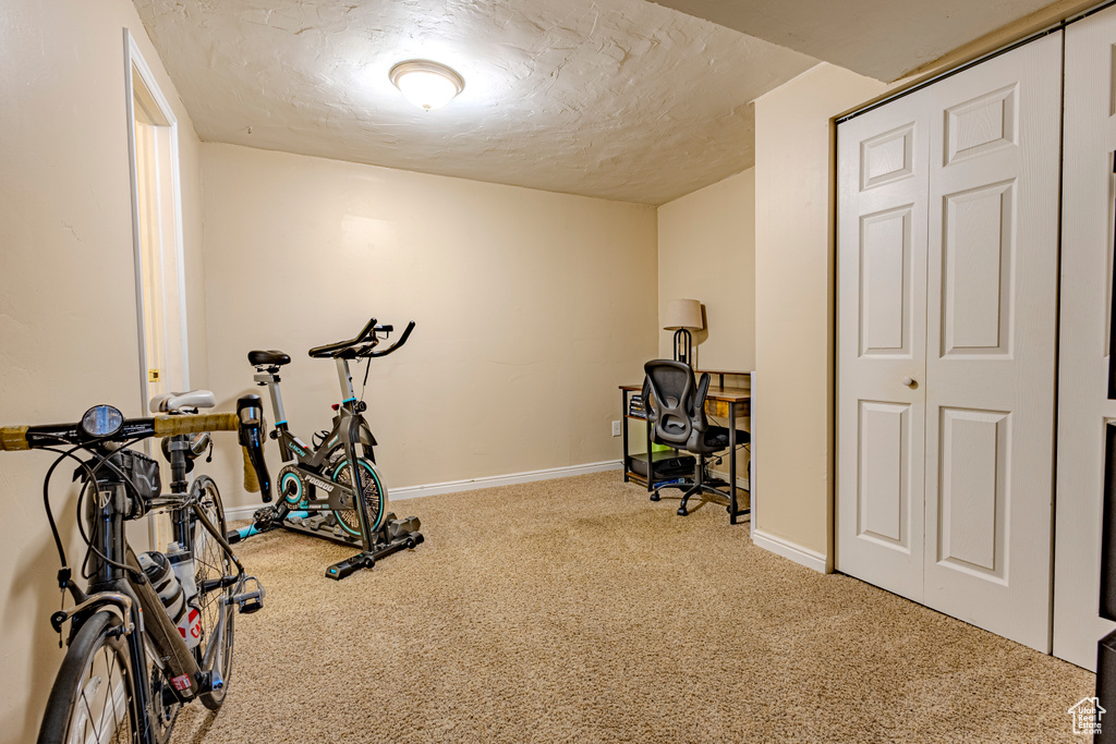 Exercise room featuring carpet flooring, a textured ceiling, and baseboards