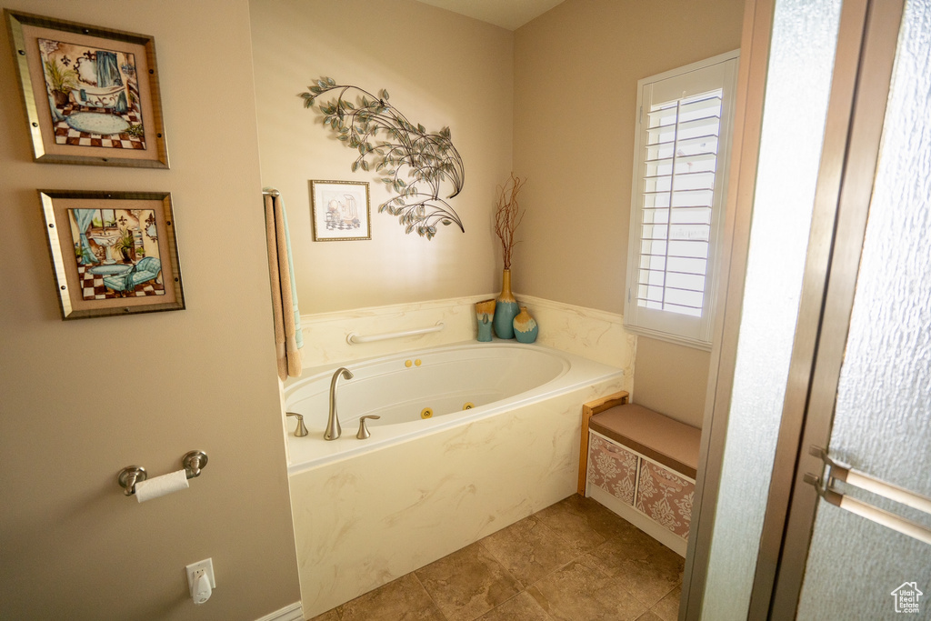 Full bath with tile patterned floors, plenty of natural light, and a jetted tub