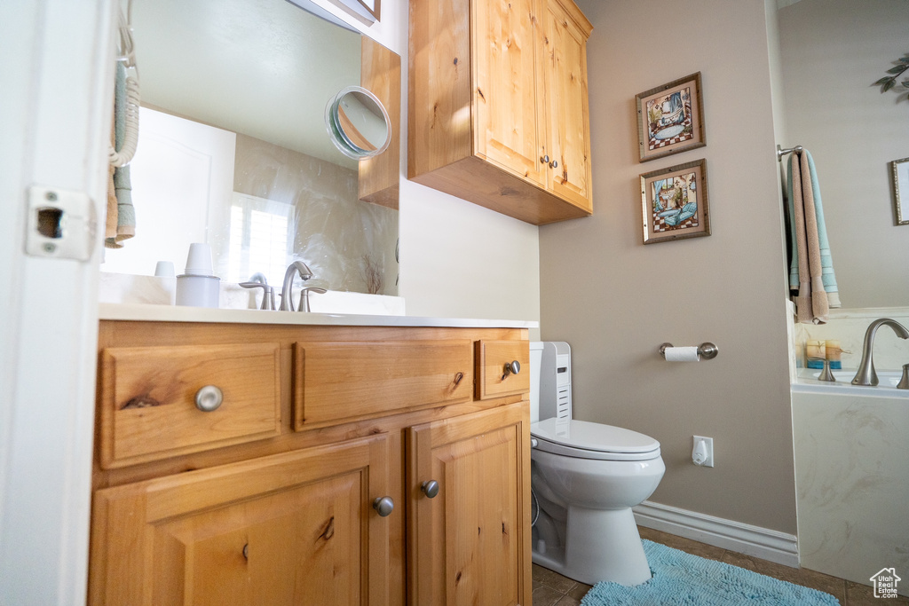 Bathroom featuring toilet, tile patterned floors, baseboards, and vanity