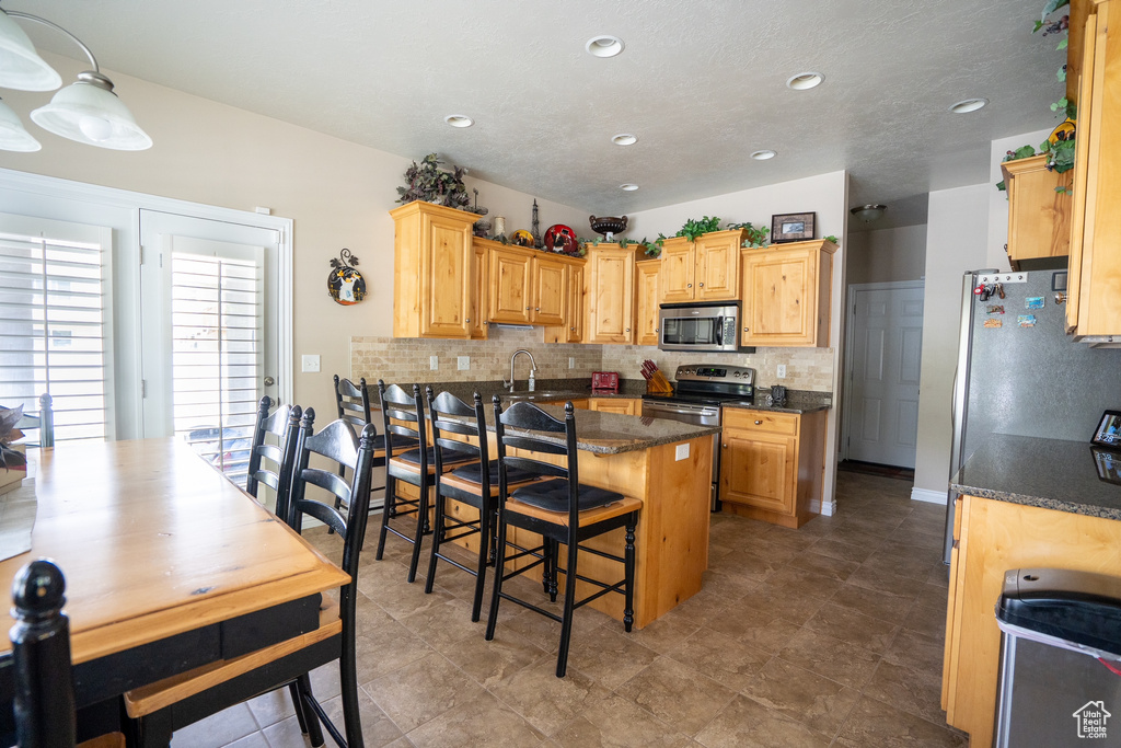 Kitchen with stainless steel appliances, recessed lighting, a kitchen breakfast bar, and tasteful backsplash