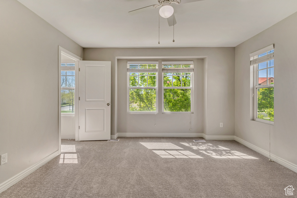 Carpeted empty room featuring ceiling fan and baseboards
