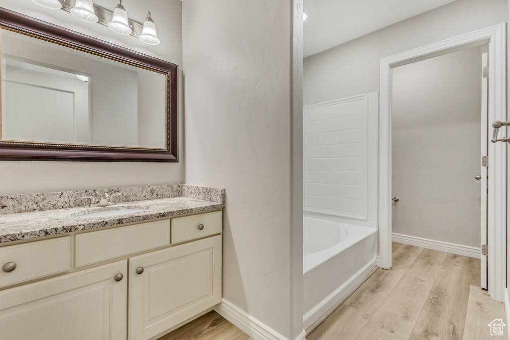 Full bath with a bathing tub, wood finished floors, vanity, and baseboards