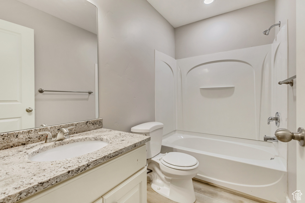 Bathroom with wood finished floors, toilet, shower / bathtub combination, and vanity
