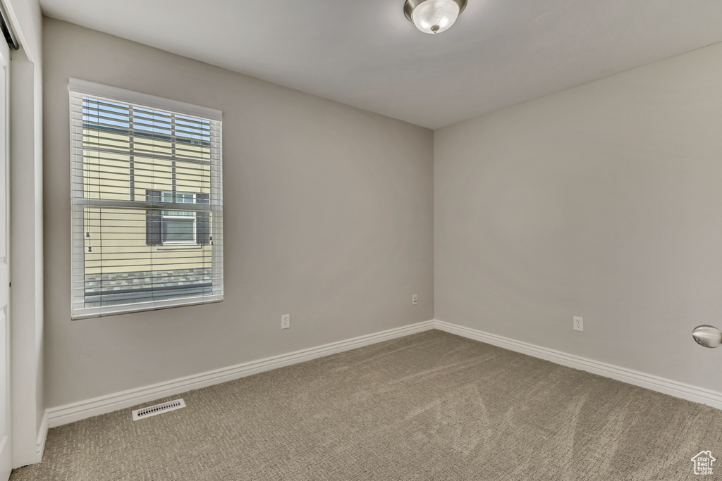 Carpeted empty room with visible vents and baseboards