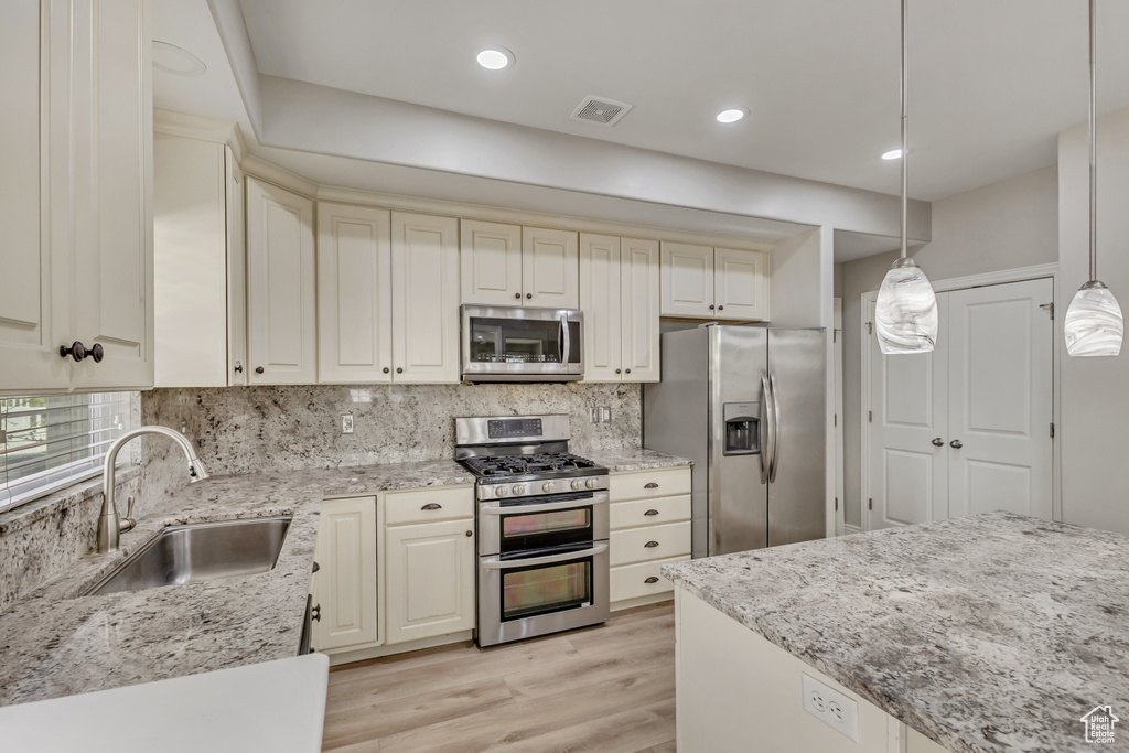 Kitchen featuring cream cabinets, a sink, appliances with stainless steel finishes, and visible vents