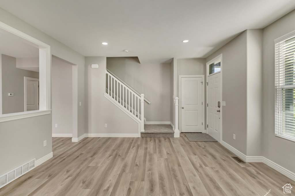 Entrance foyer with baseboards, visible vents, stairway, and light wood-style flooring