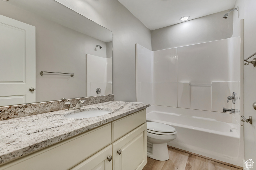 Bathroom featuring wood finished floors, toilet, shower / tub combination, and vanity