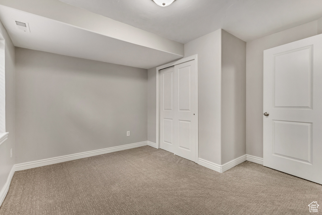 Unfurnished bedroom with visible vents, a closet, carpet flooring, and baseboards