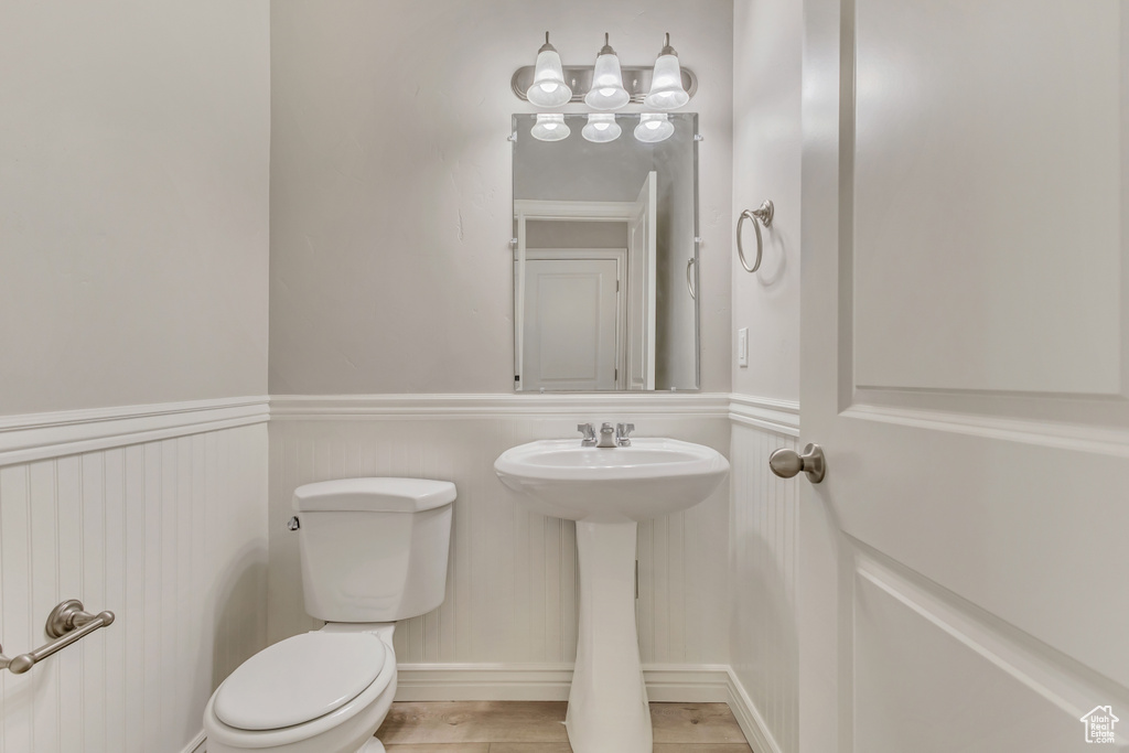 Half bath with a wainscoted wall, toilet, and a sink