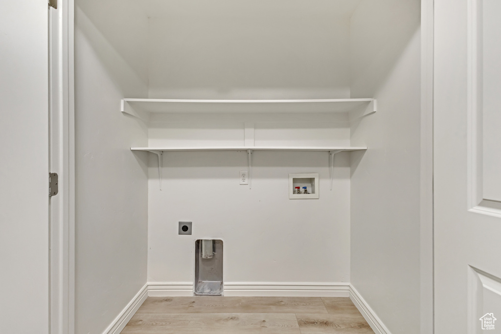 Laundry area with hookup for an electric dryer, washer hookup, baseboards, light wood finished floors, and laundry area