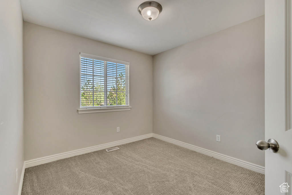 Carpeted empty room with visible vents and baseboards