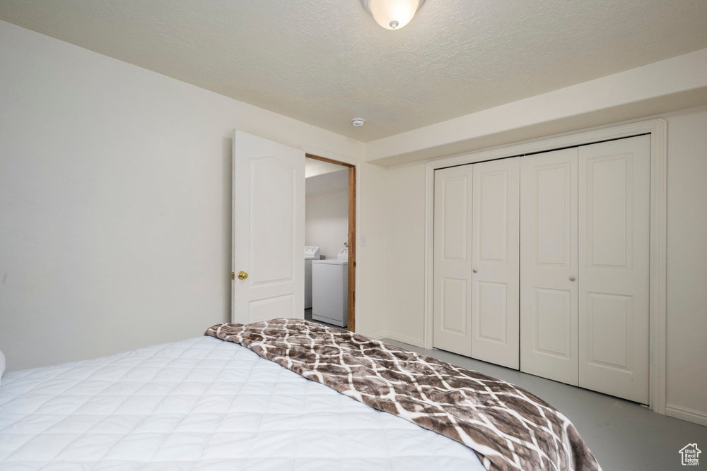 Bedroom featuring a closet, a textured ceiling, and washer / dryer