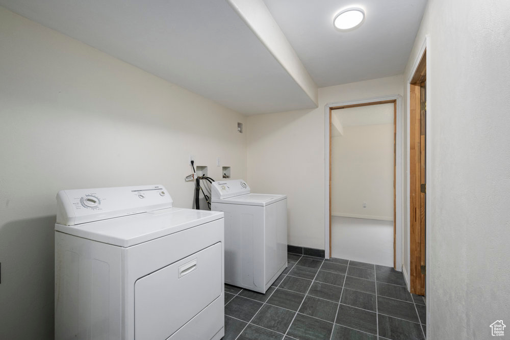 Clothes washing area with laundry area, dark tile patterned floors, and washer and dryer
