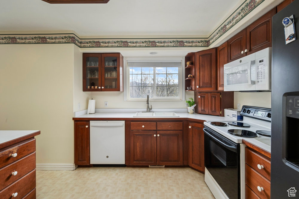 Kitchen with a sink, white appliances, and light countertops