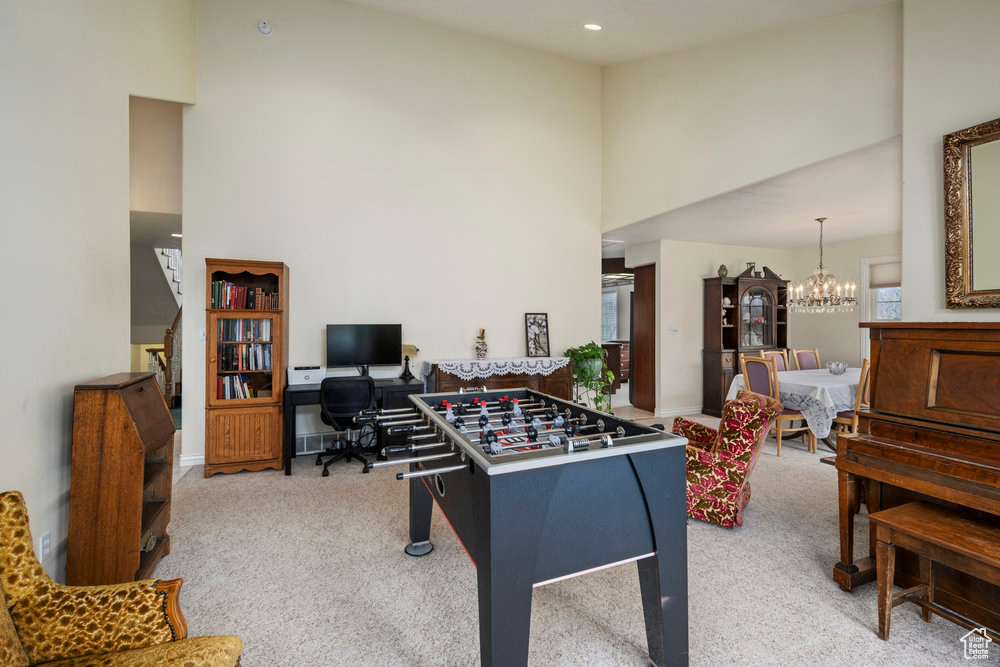 Game room with carpet floors, baseboards, a chandelier, and a towering ceiling