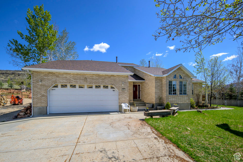 Ranch-style house featuring brick siding, driveway, a front yard, and a garage