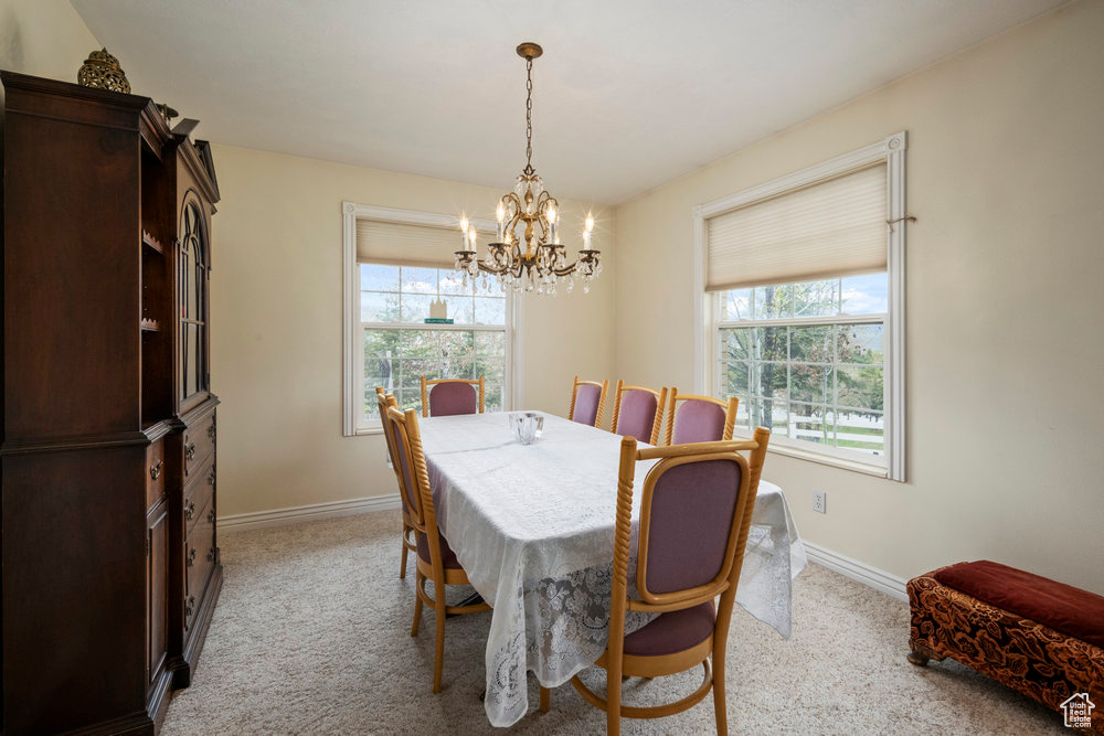 Dining space with a notable chandelier, light carpet, and a healthy amount of sunlight