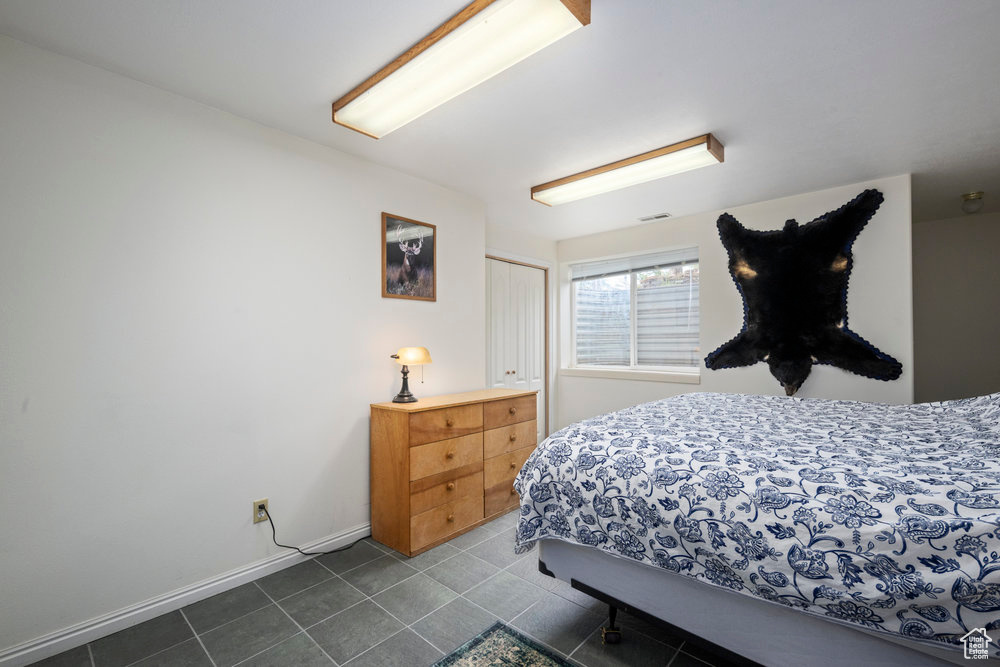 Bedroom with dark tile patterned floors, baseboards, a closet, and visible vents