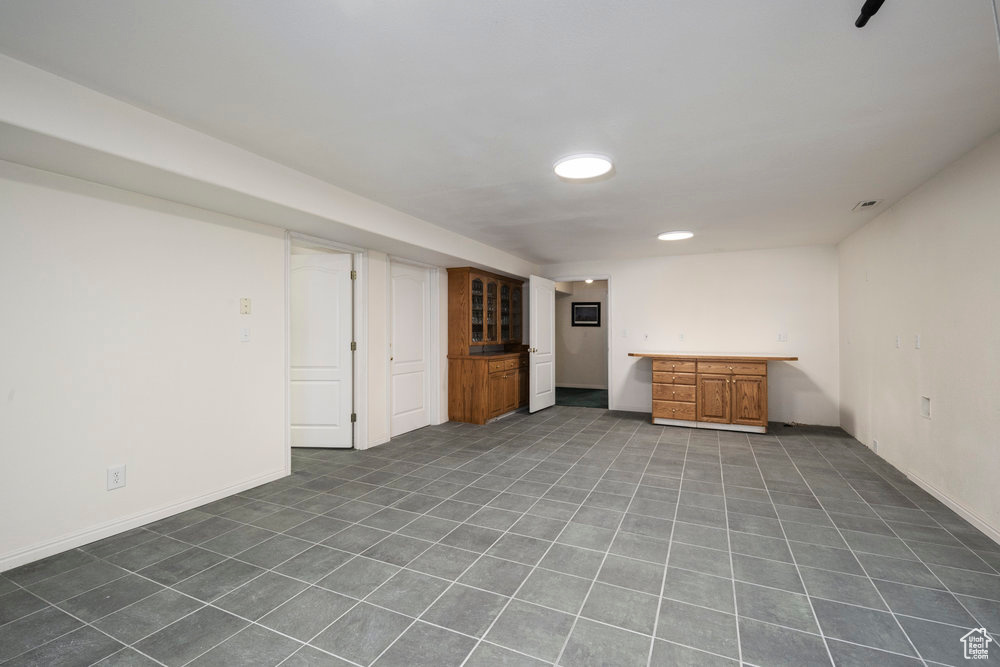 Finished below grade area with dark tile patterned flooring, bar area, and baseboards