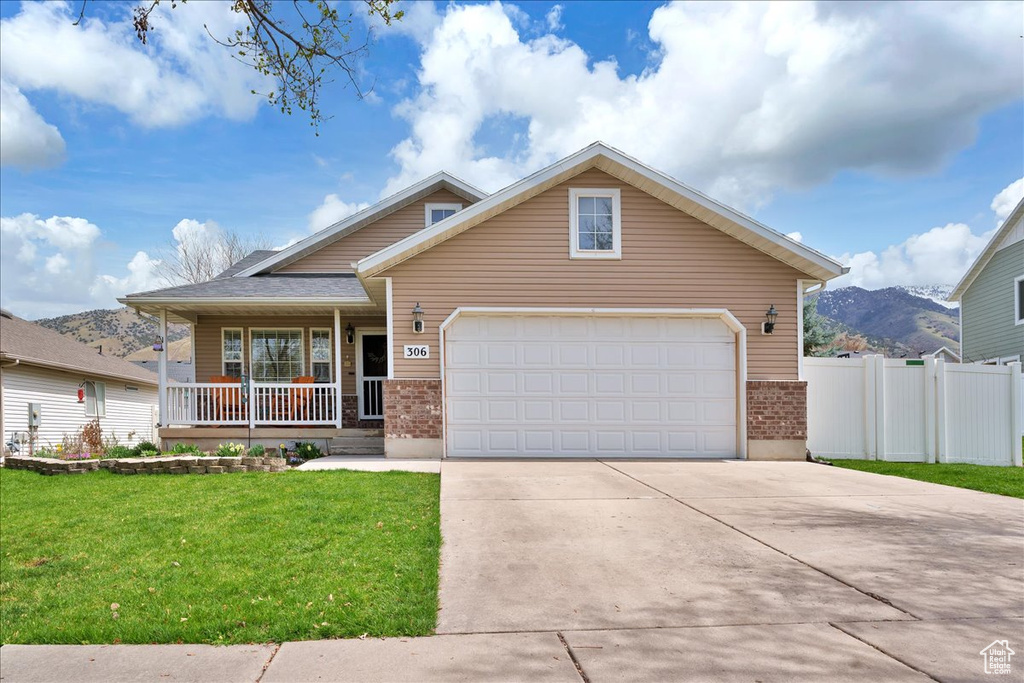 Traditional-style house with a front lawn, fence, covered porch, brick siding, and driveway