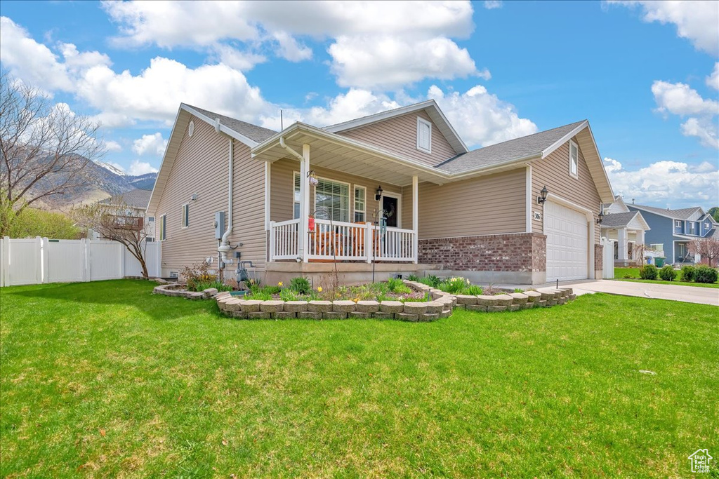 View of front of house with fence, an attached garage, a front lawn, concrete driveway, and covered porch