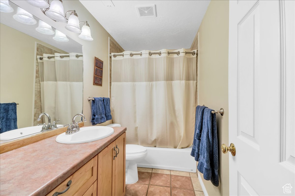 Bathroom with tile patterned flooring, vanity, toilet, shower / bath combo with shower curtain, and visible vents
