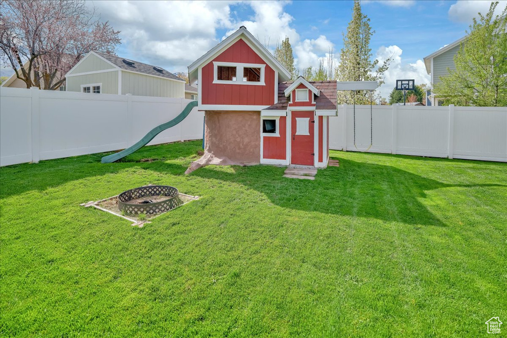 View of outdoor structure with an outdoor structure, a fire pit, and a fenced backyard
