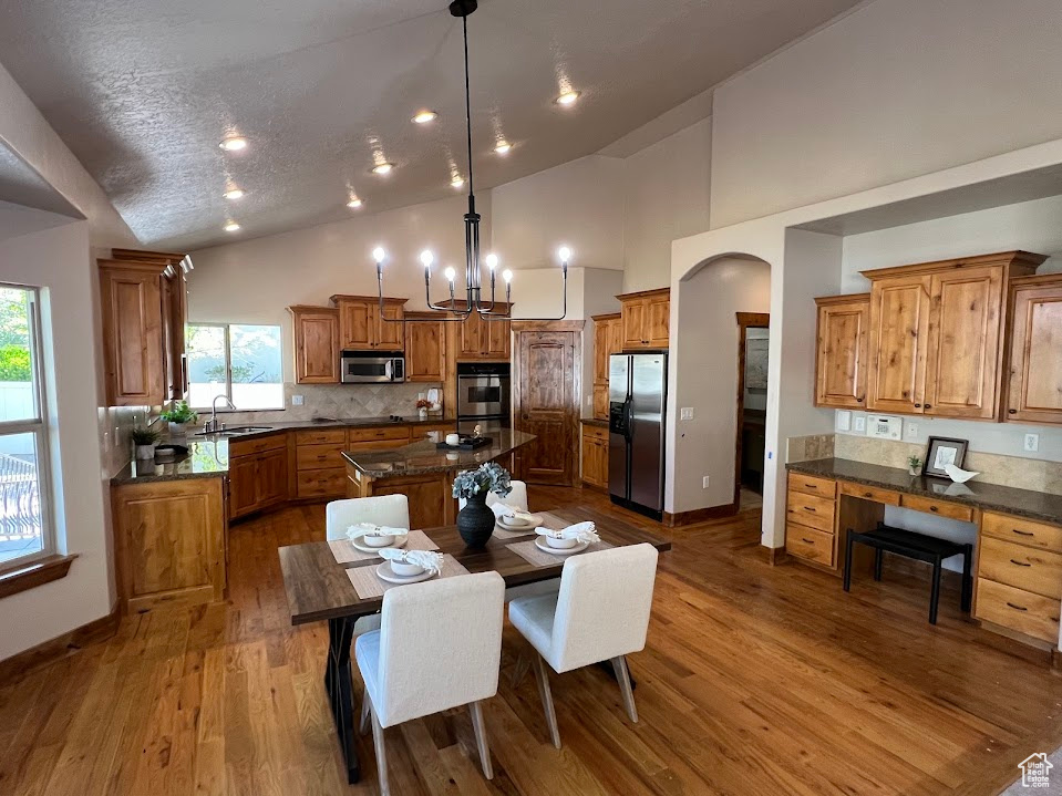 Kitchen with decorative backsplash, brown cabinetry, a center island, a sink, and stainless steel appliances