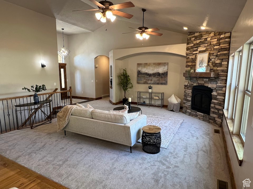 Living room featuring a ceiling fan, visible vents, arched walkways, a fireplace, and carpet