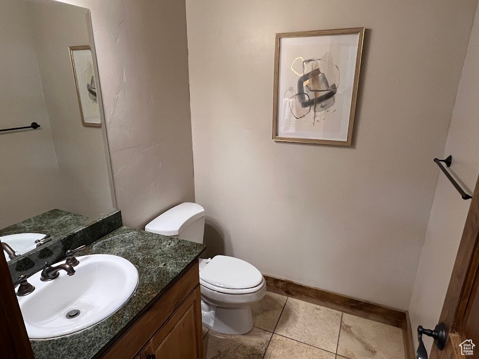 Bathroom featuring toilet, tile patterned floors, baseboards, and vanity