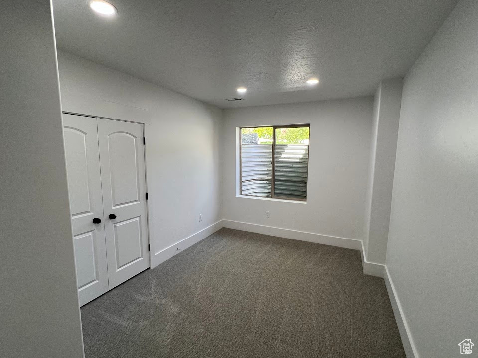 Empty room featuring dark colored carpet, recessed lighting, baseboards, and visible vents