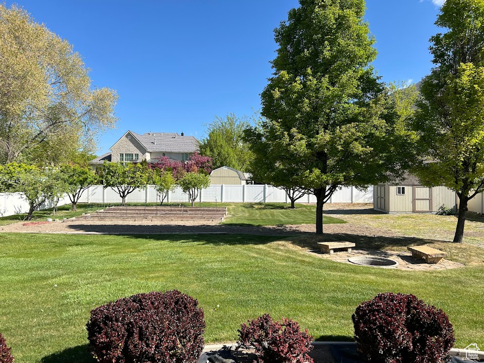 View of yard featuring fence, a storage unit, and an outdoor structure
