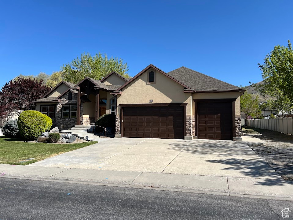 View of front of house featuring fence, stone siding, stucco siding, concrete driveway, and an attached garage