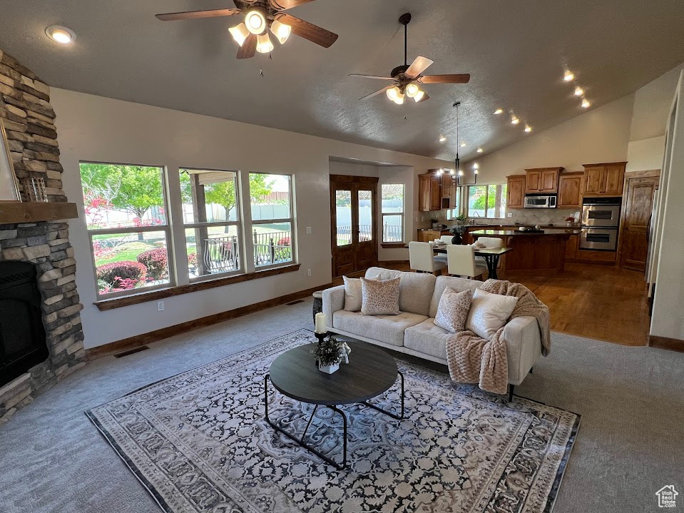 Carpeted living area with a ceiling fan, baseboards, vaulted ceiling, and visible vents