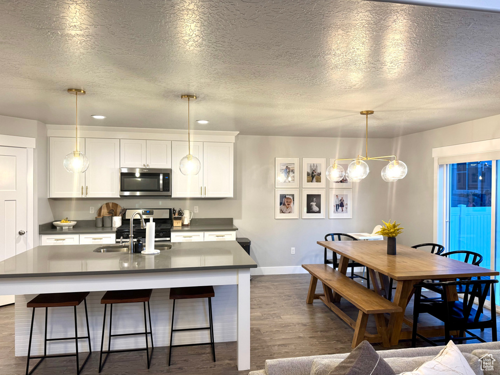 Kitchen with a textured ceiling, dark countertops, appliances with stainless steel finishes, baseboards, and dark wood-style floors