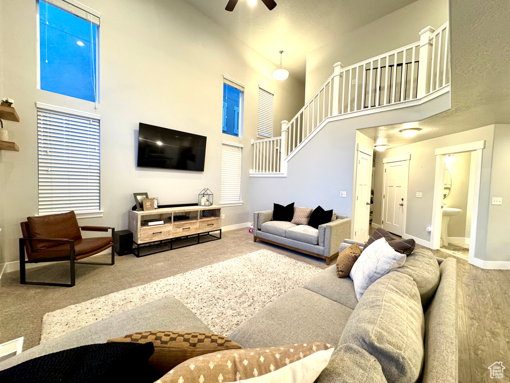 Living area featuring baseboards, a high ceiling, ceiling fan, and carpet