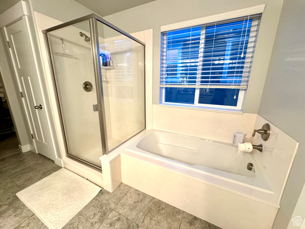 Bathroom with tile patterned flooring, a bath, and a stall shower