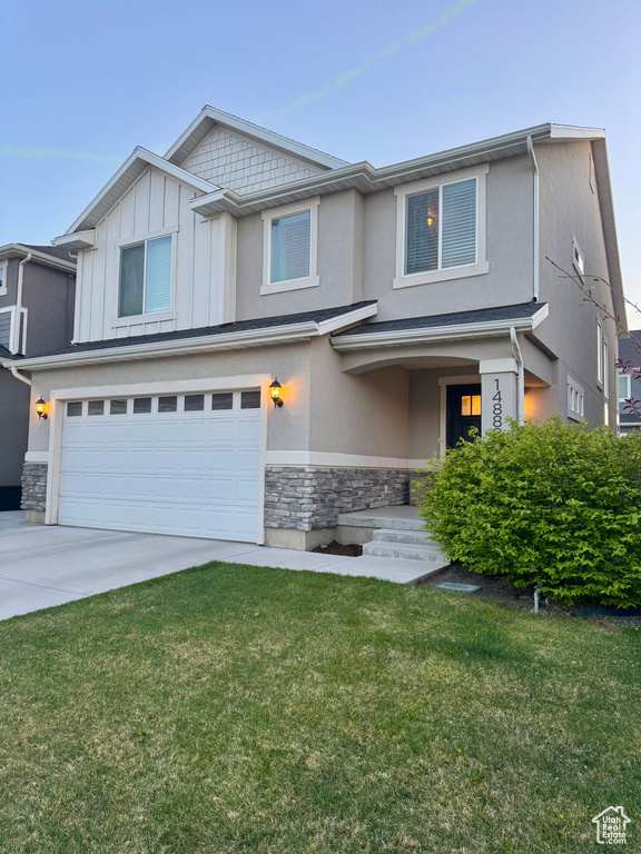 View of front of house with a garage, a front lawn, stone siding, stucco siding, and concrete driveway