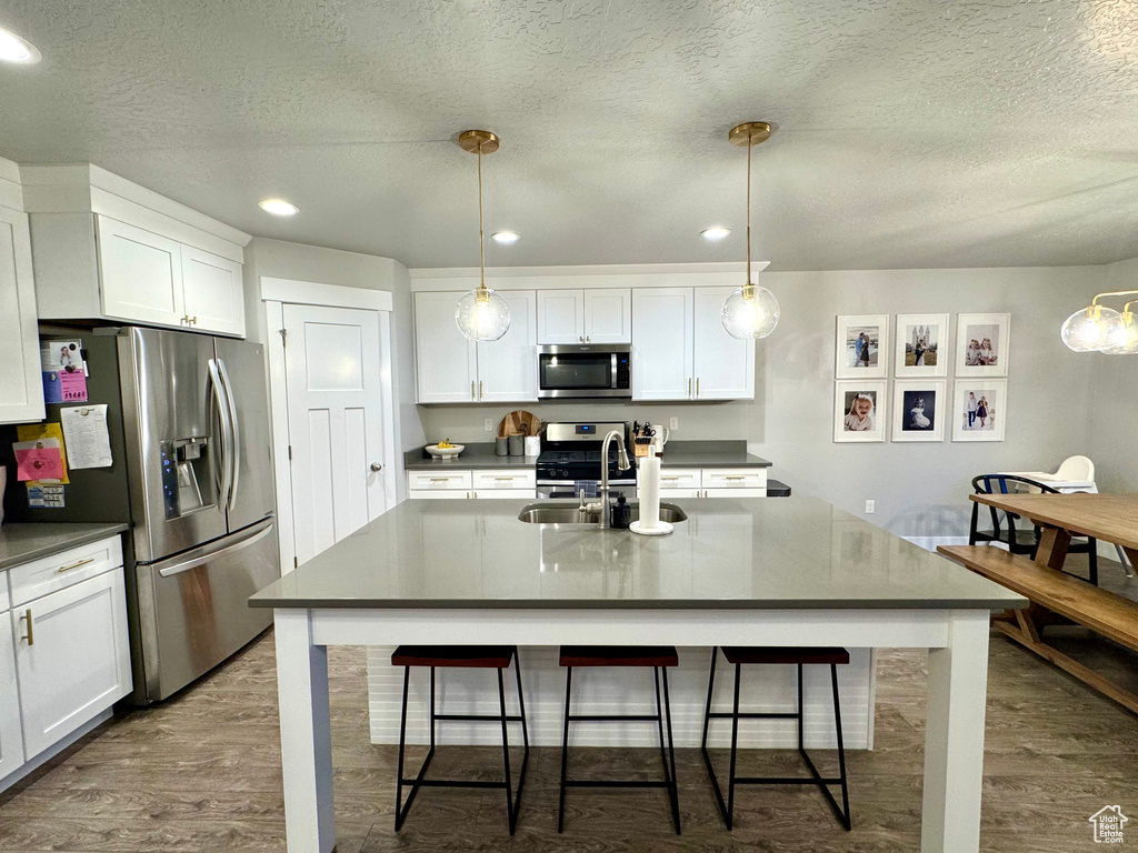 Kitchen featuring dark countertops, stainless steel appliances, dark wood-style floors, and white cabinetry