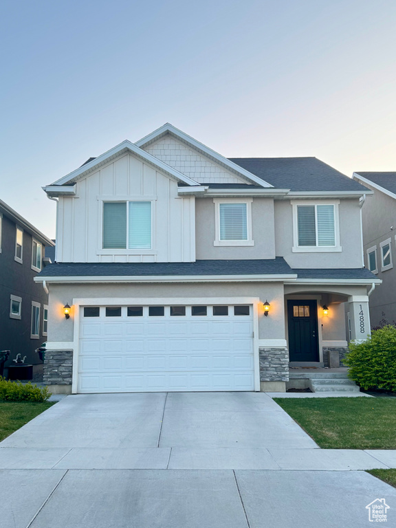 View of front facade with concrete driveway, stone siding, and a garage