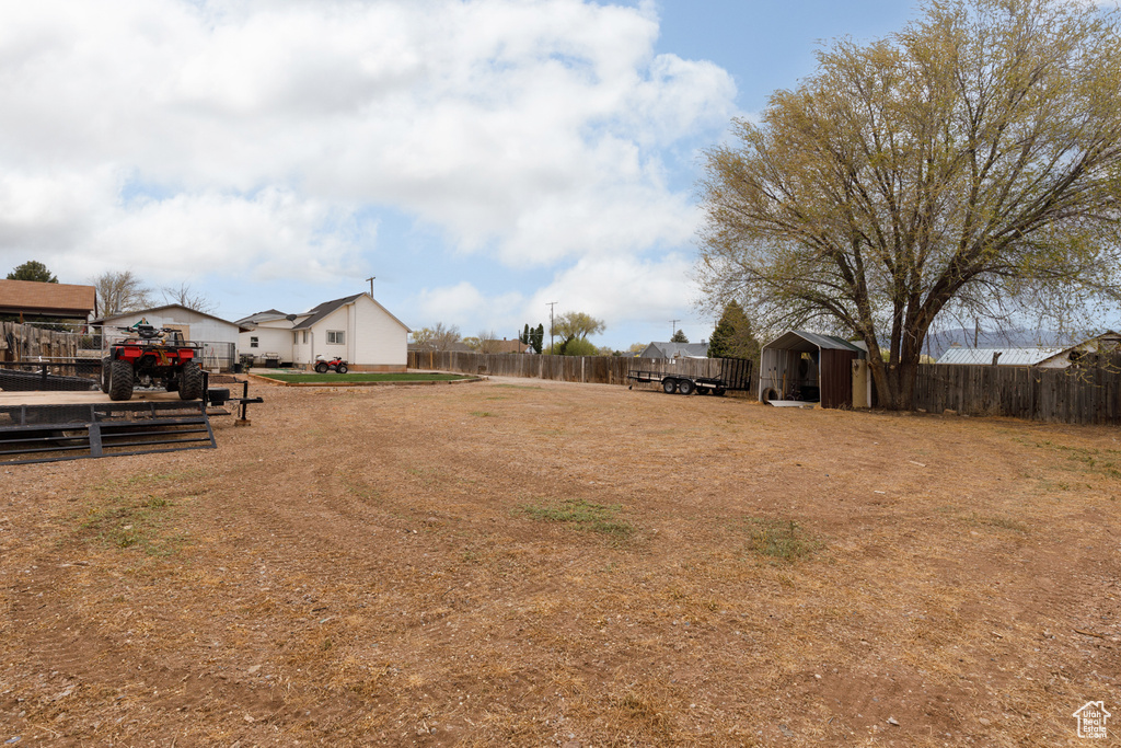 View of yard with a storage shed, a residential view, fence, and an outbuilding