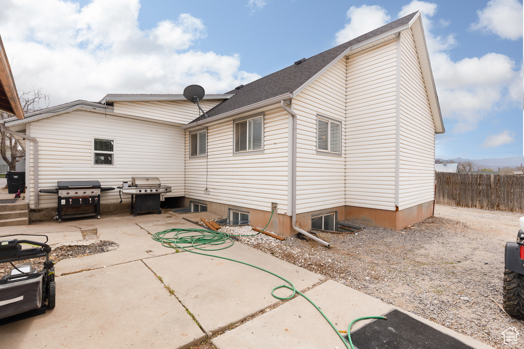 Back of house with a patio, roof with shingles, and fence