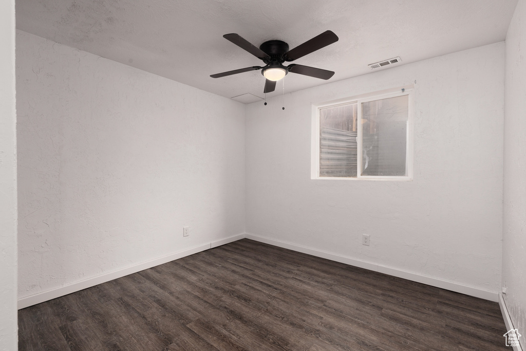 Spare room featuring baseboards, ceiling fan, dark wood-style flooring, and visible vents