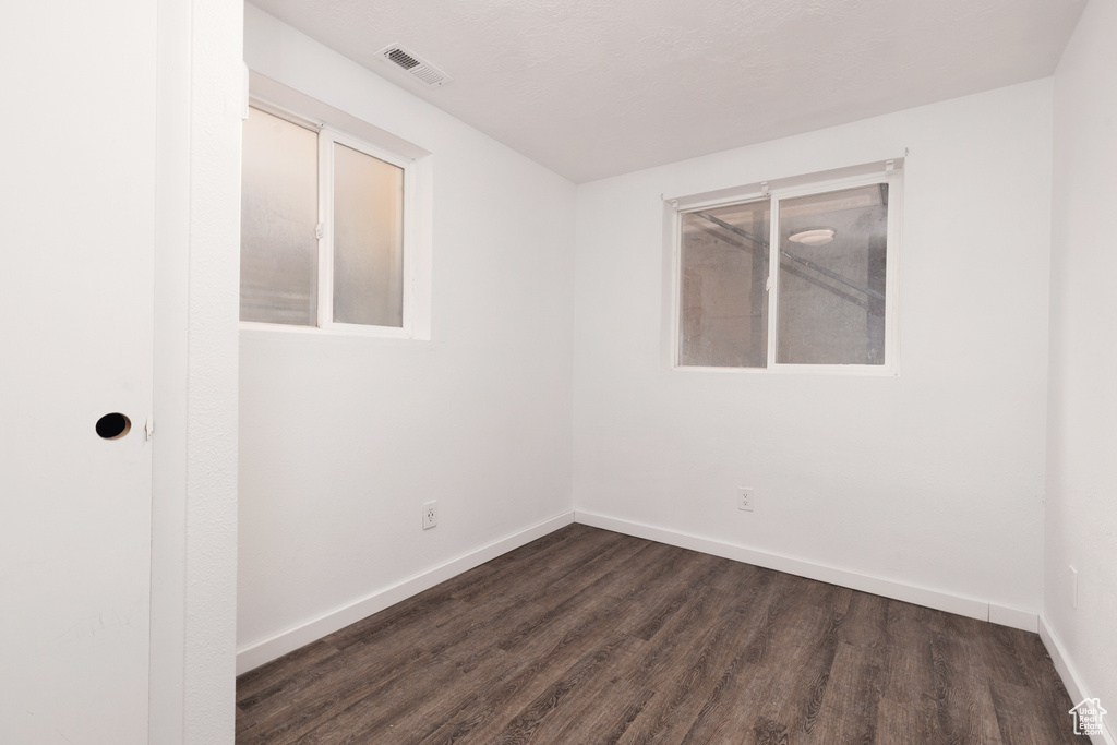 Unfurnished room with baseboards, visible vents, and dark wood-type flooring