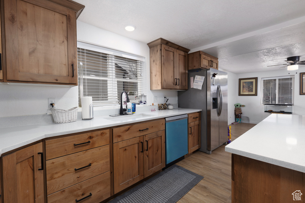 Kitchen featuring a sink, stainless steel fridge, light countertops, a ceiling fan, and dishwasher