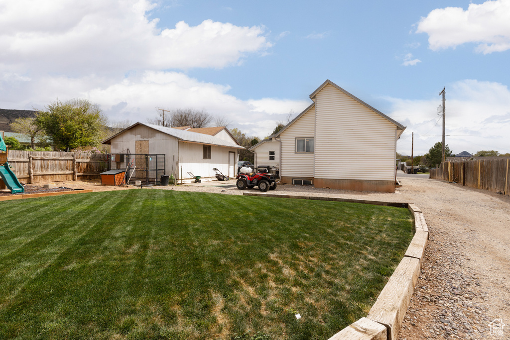 Back of house with a fenced backyard, a playground, and a lawn