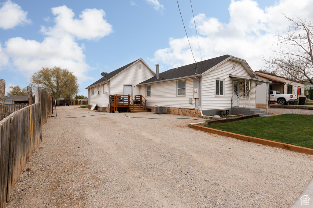 Exterior space with central air condition unit, a yard, a deck, and fence