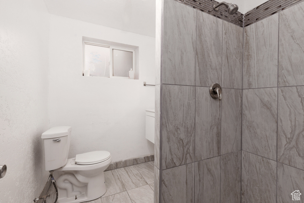 Bathroom featuring a tile shower and toilet