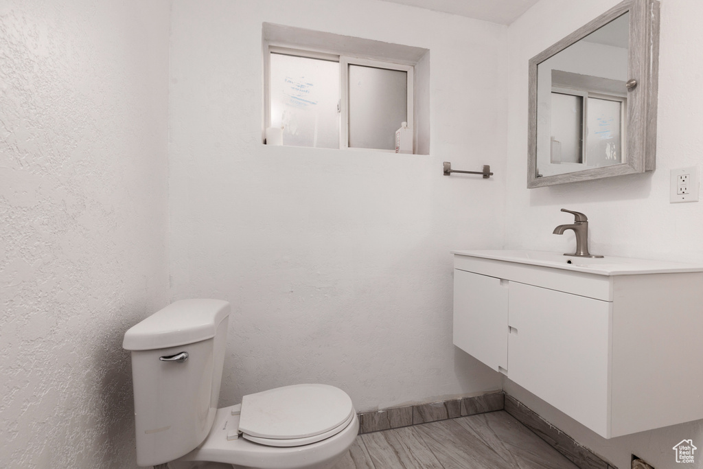 Bathroom with vanity, baseboards, wood finished floors, and toilet