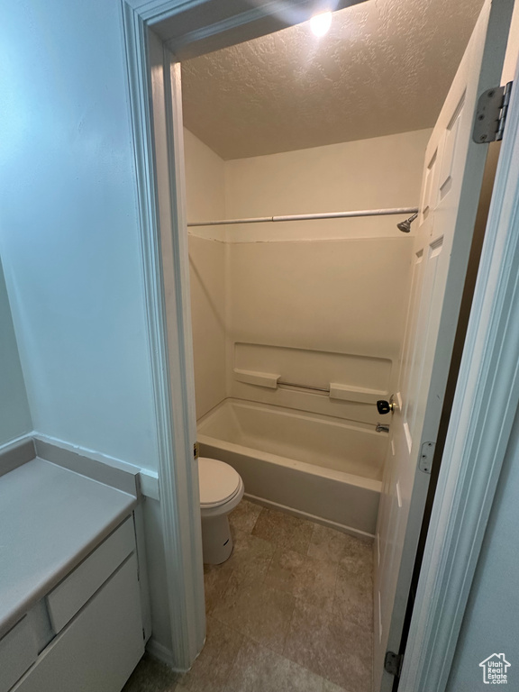 Full bathroom featuring toilet, a textured ceiling, and washtub / shower combination
